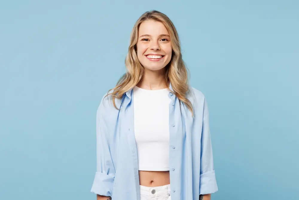 Smiling young blonde girl infront of a blue back drop
