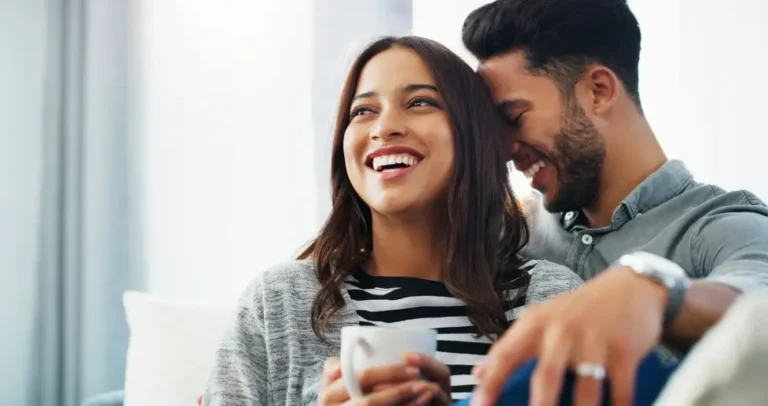 Happy couple sitting on a couch, smiling and laughing