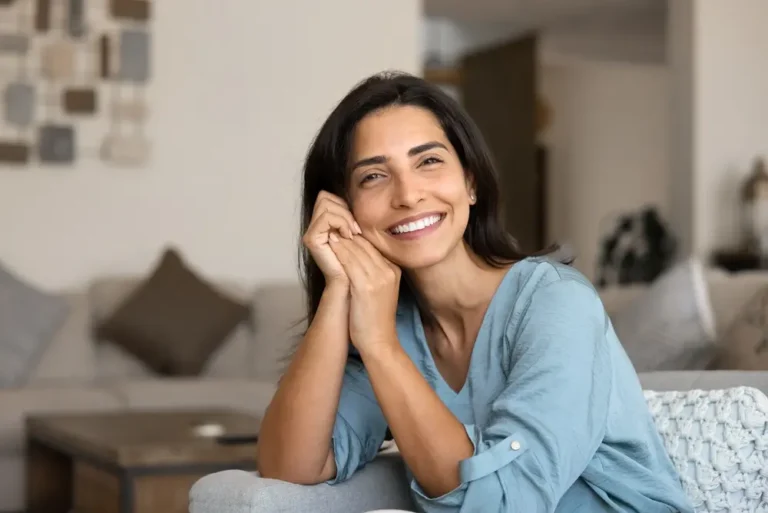 Happy, smiling woman sitting on her couch at home